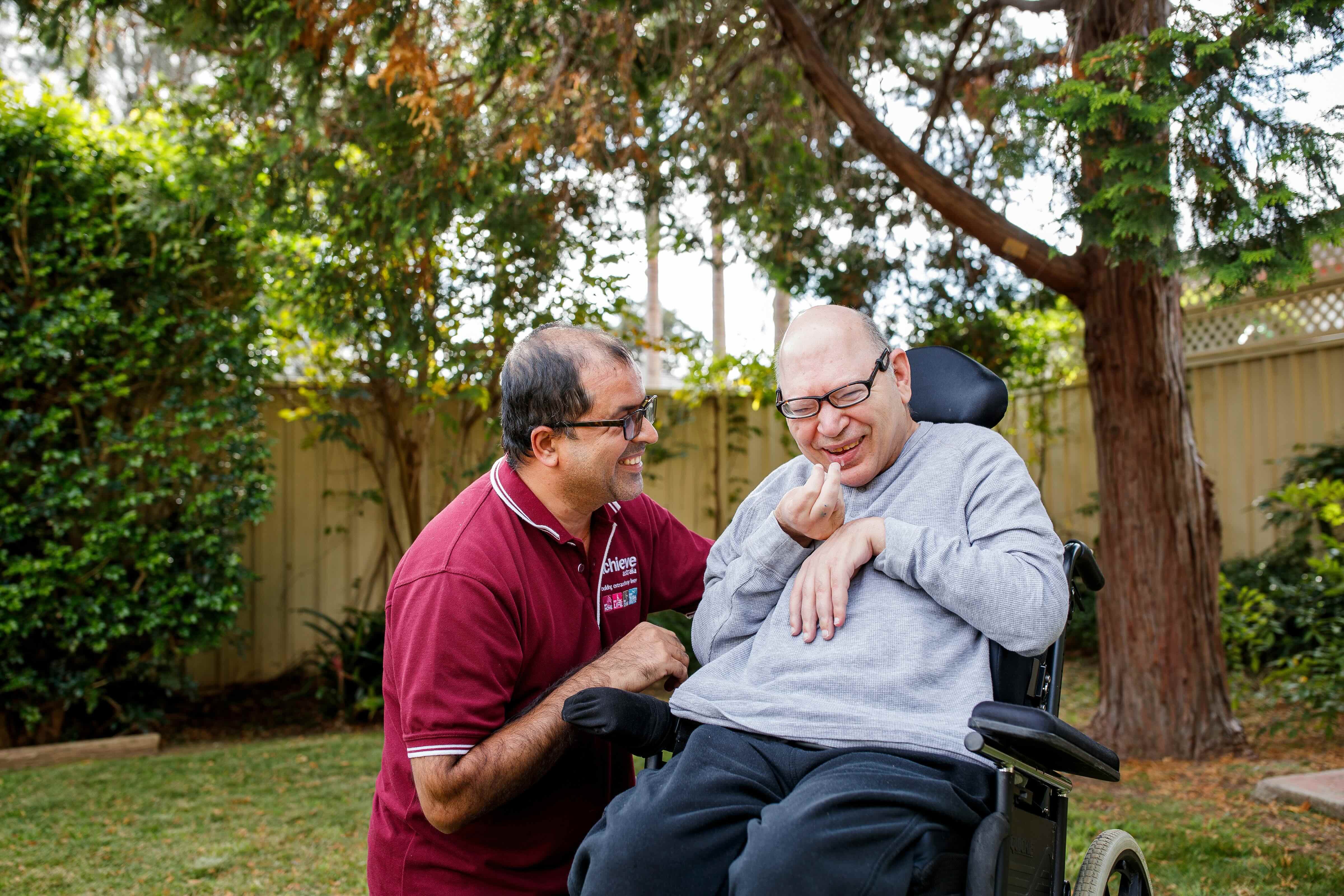 Man with disability smiling with support worker in garden