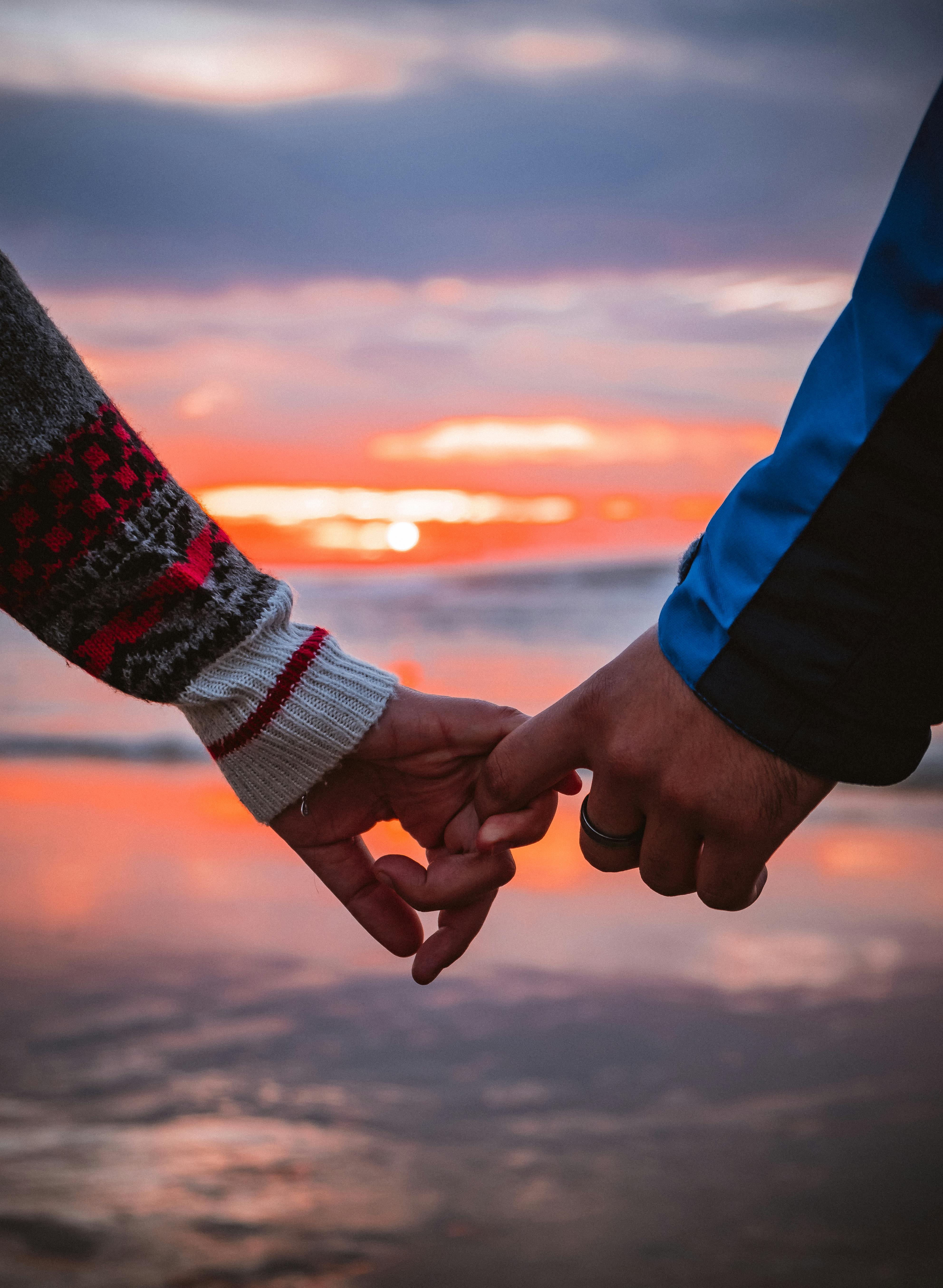 two holding hands at the sunset