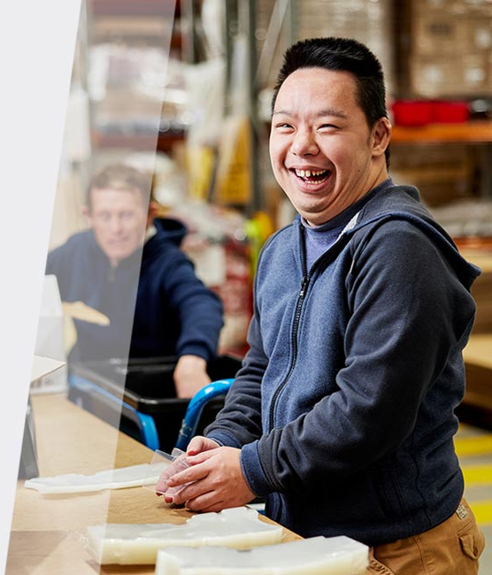 A man with disability in a packing factory smiling at work