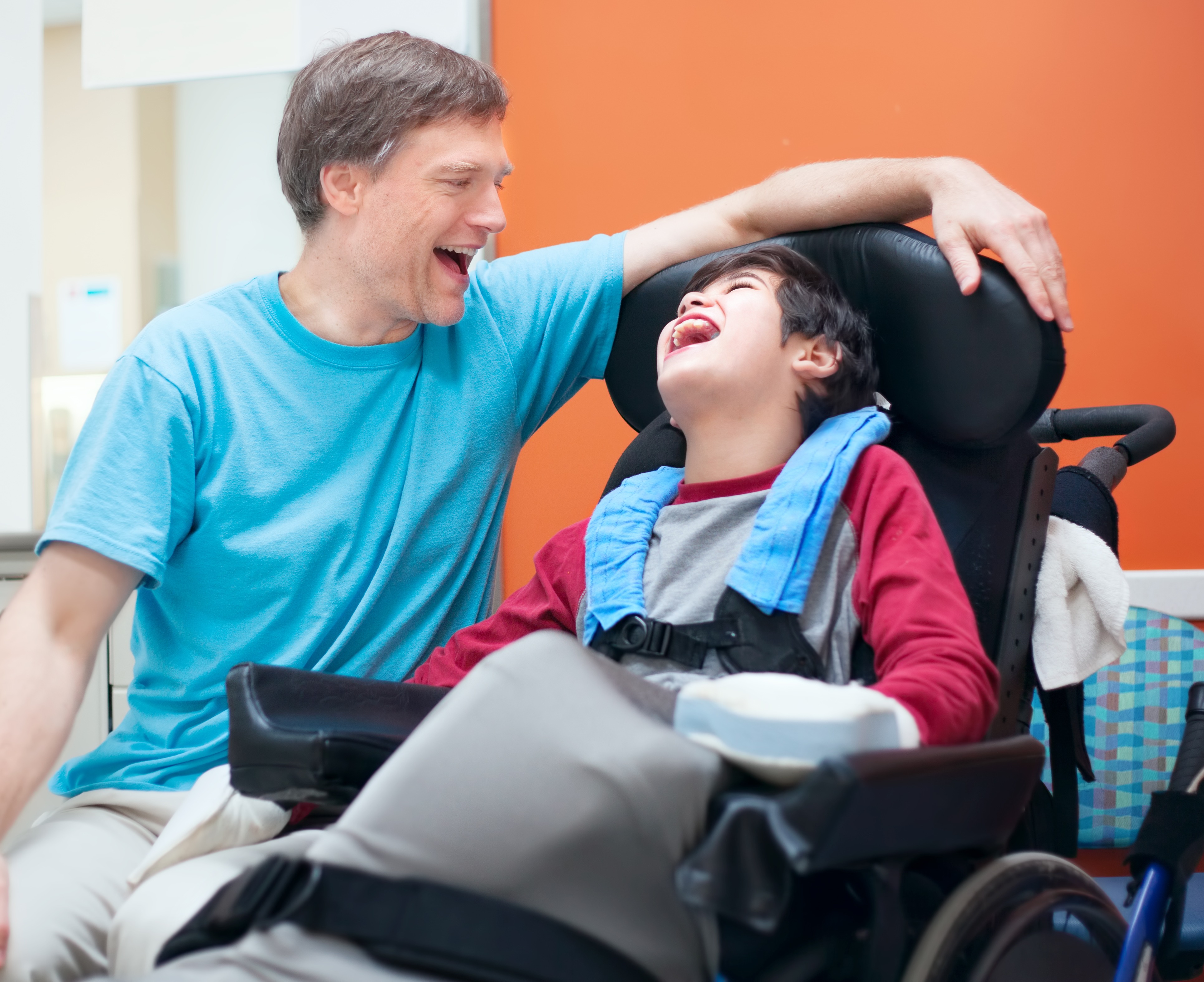 carer and a boy with disability is laughing together and having a good time